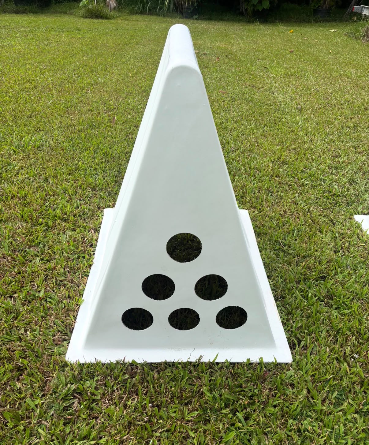 White one-piece A-frame coop on a lawn, vent end with six circular holes