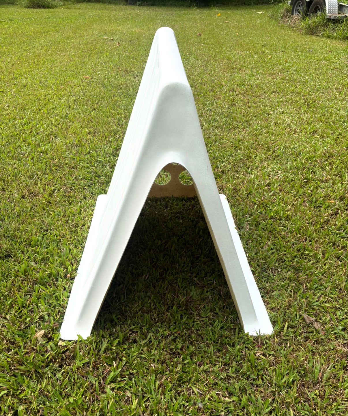 White one-piece A-frame coop on a lawn, open end looking through the shell
