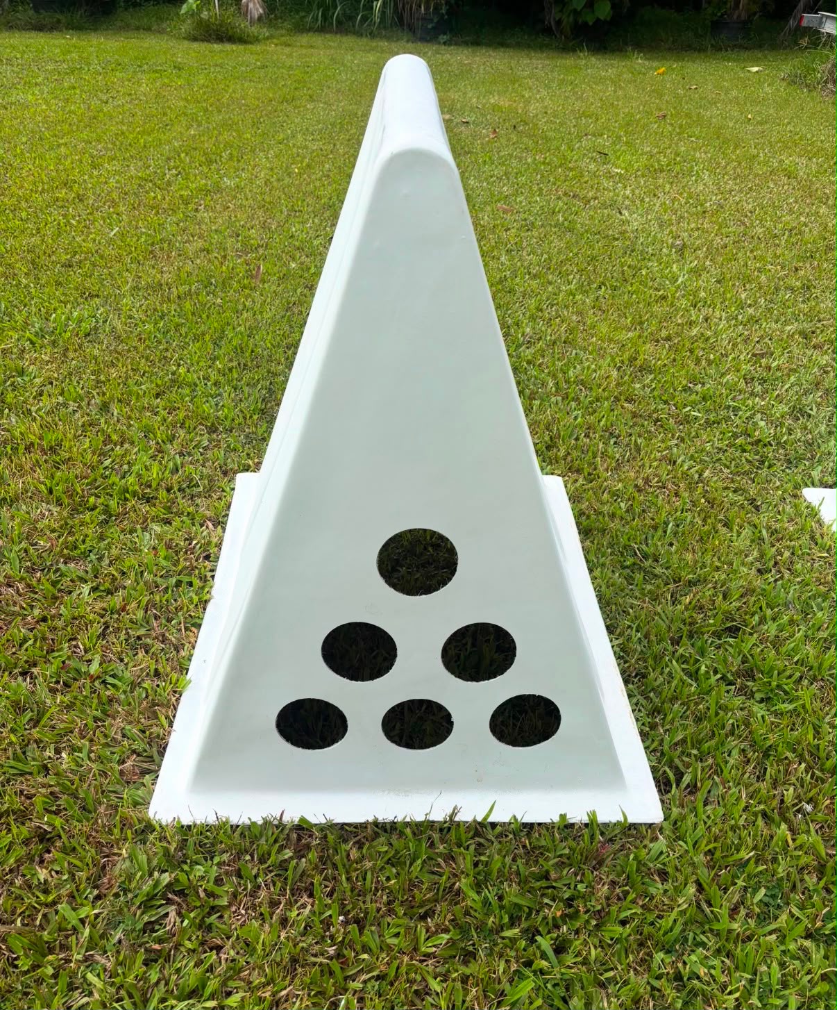 Low-angle live photo of a white A-frame coop on grass, six-hole vent end